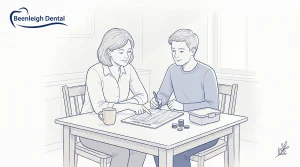 A parent and family member plan a dental budget at the kitchen table with a basic sheet, coins and a mug.
